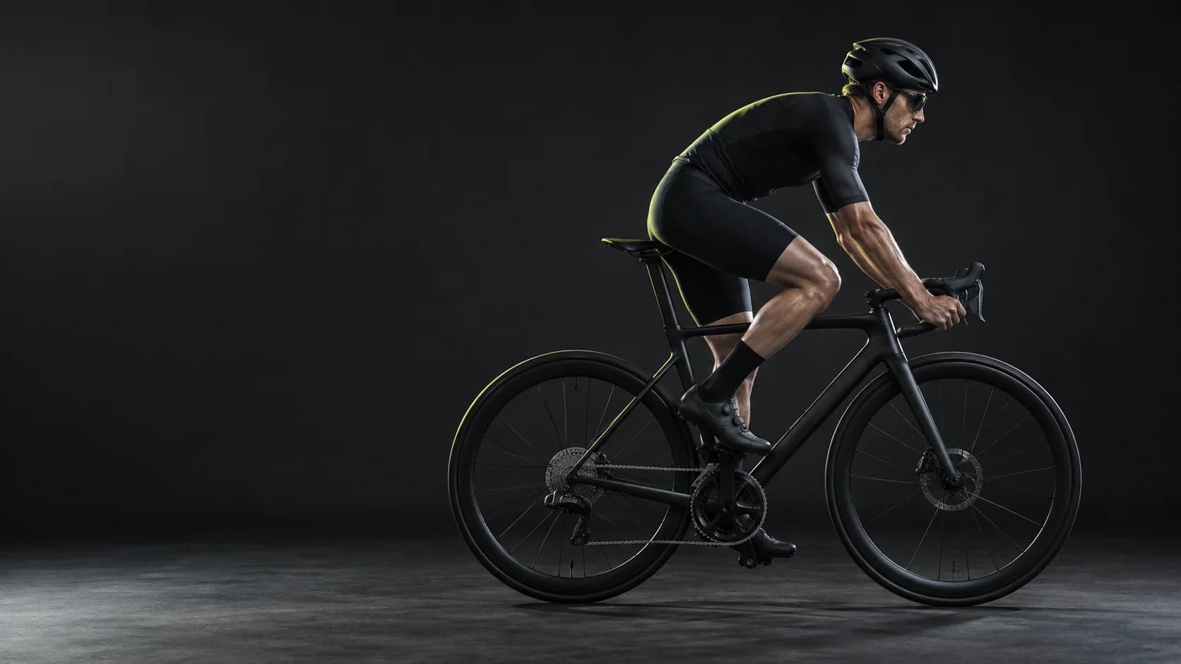 Side profile of a cyclist in an aerodynamic riding position on a road bike, in a dark studio
